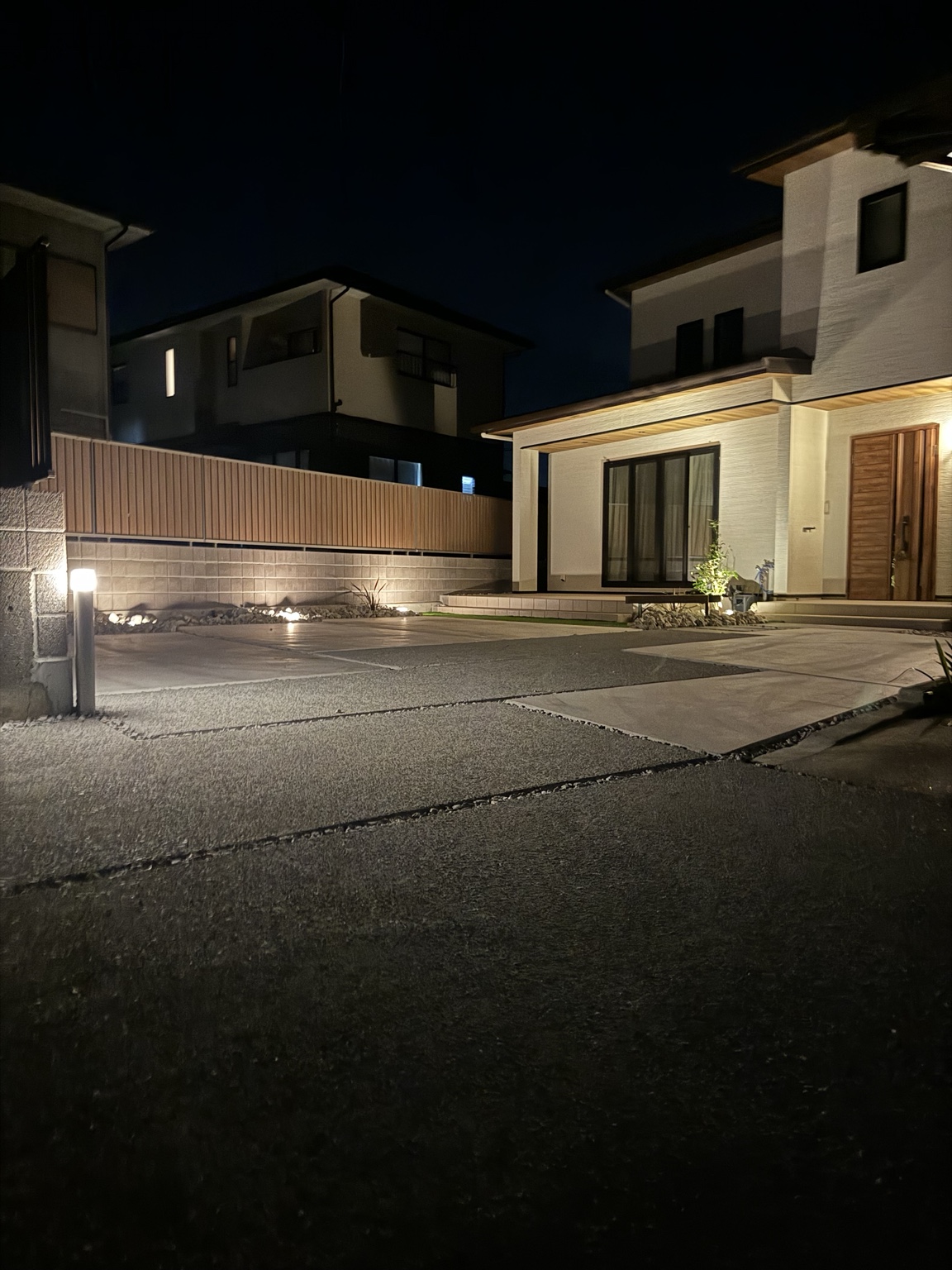 温かな照明が灯る夜のアプローチとフェンス