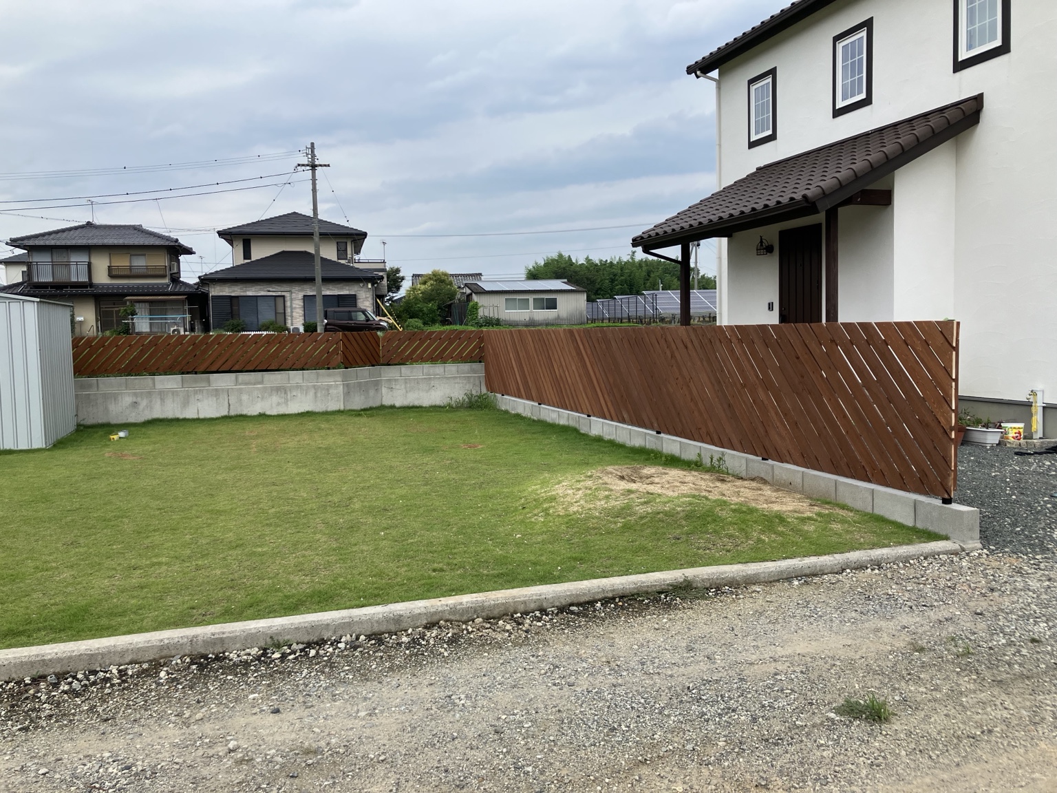斜めの板張りフェンスと芝生の庭